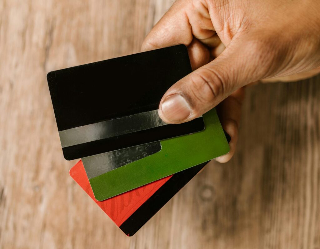 A hand holding multiple credit cards on a wooden background, emphasizing payment and finance themes.